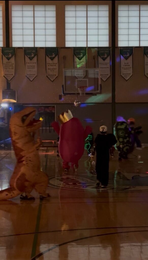 Costumed families dancing in the gym during Halloween Howl.