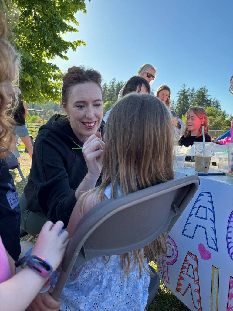 A volunteer painting a child’s face at the Ice Cream Social.