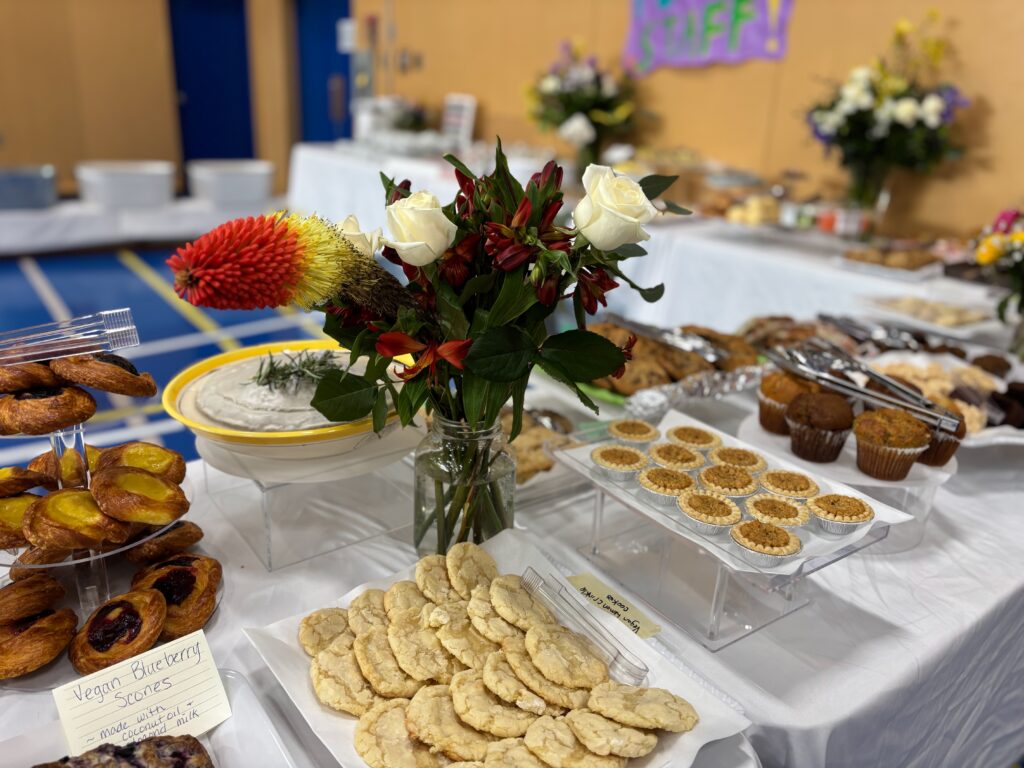 A staff appreciation lunch buffet decorated with flowers and baked goods.